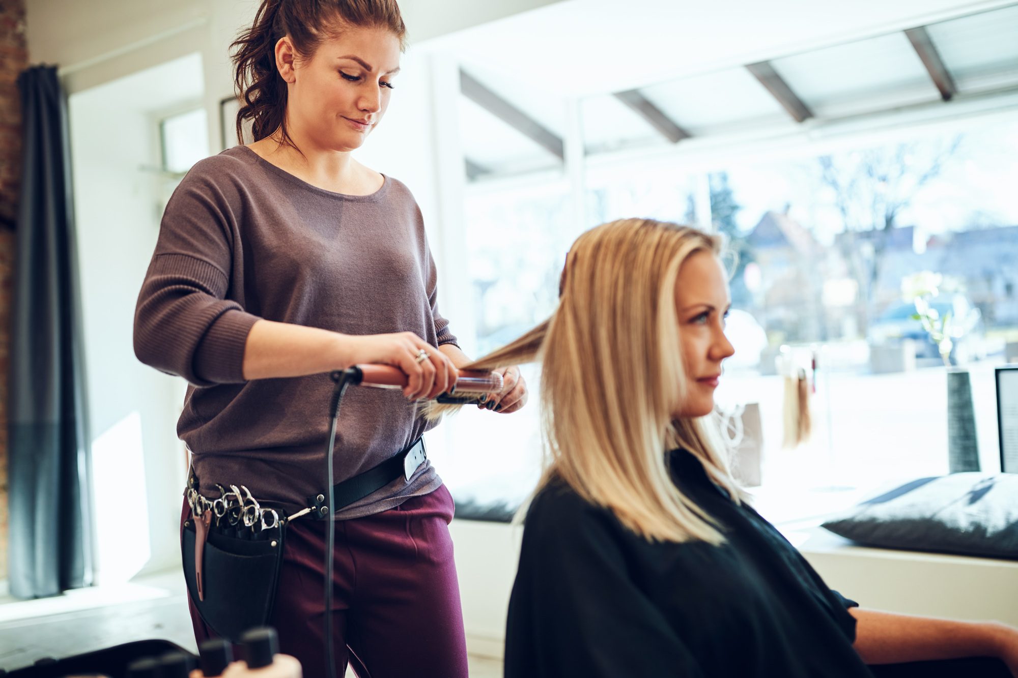 Hairdresser Straightening A Female Client S Hair In Her Salon.jpg